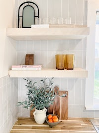 a kitchen with wooden shelves and a bowl of oranges