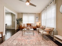 a living room with brown furniture and a ceiling fan